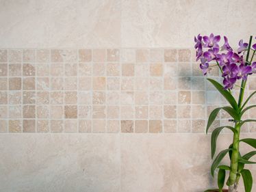 Orchidea davanti a una parete di mosaico con travertino chiaro