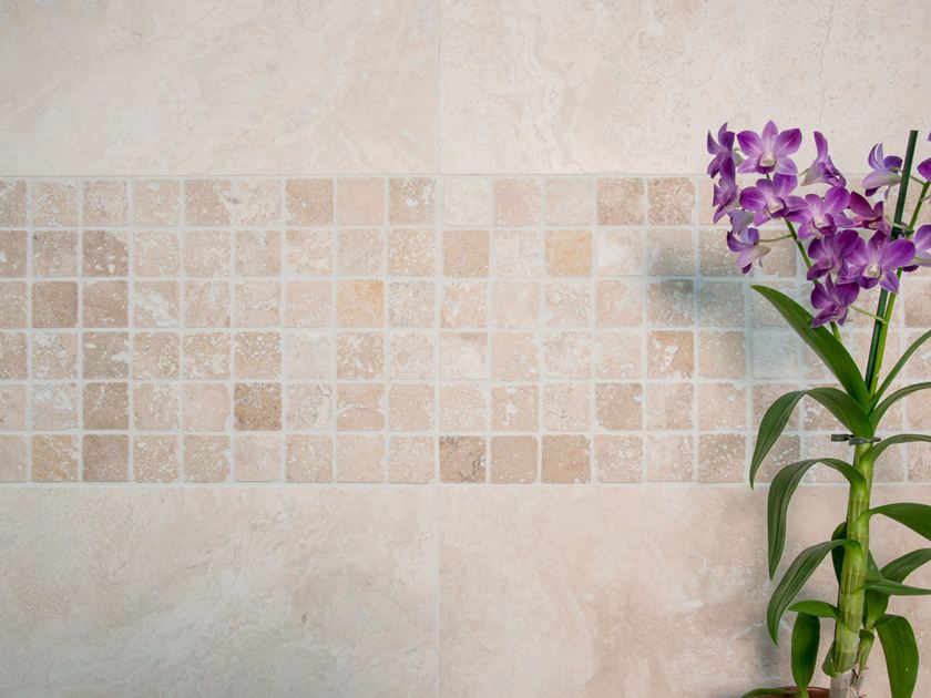 Orchidea davanti a una parete di mosaico con travertino chiaro