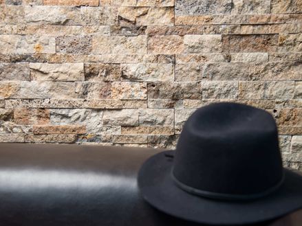 Cappello nero davanti al rivestimento delle pareti di Scabas
