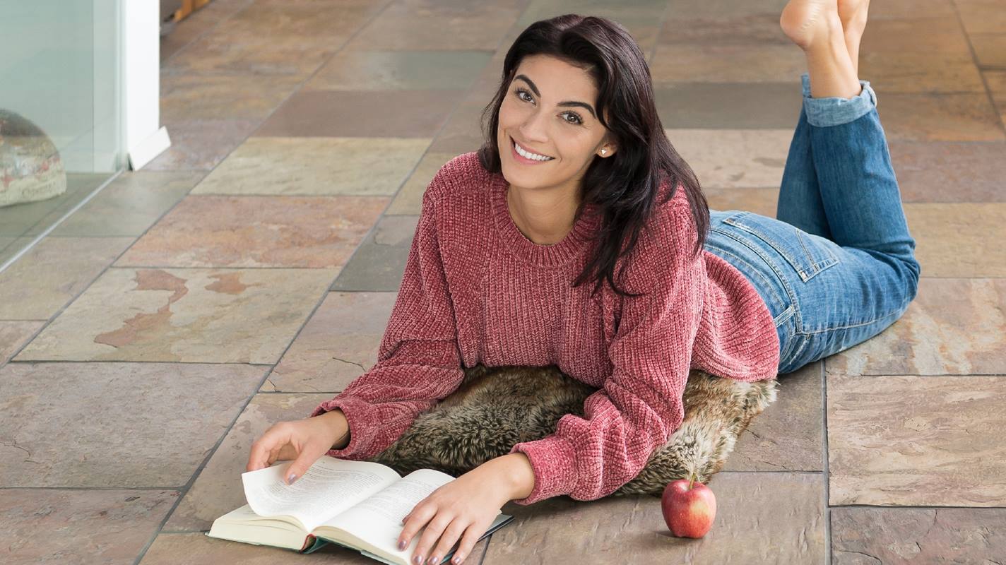 Donna sdraiata sul pavimento di ardesia Peacock Multicolor e leggere un libro