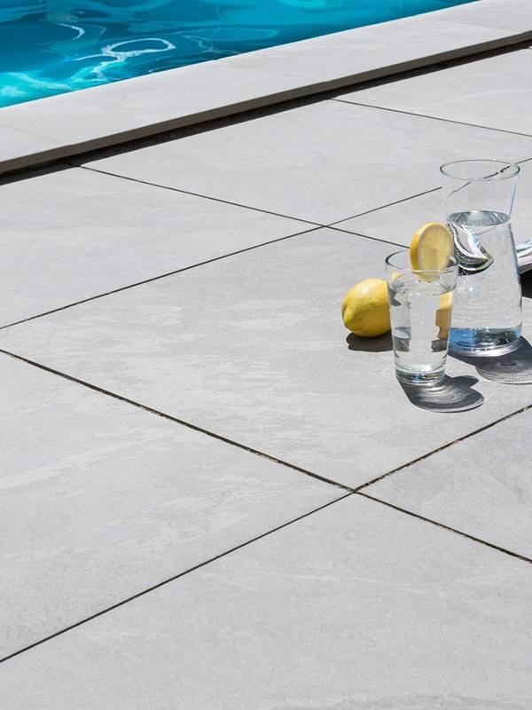 Caraffa per l'acqua e limoni sulle piastrelle della terrazza in Alpine Grey look mobile