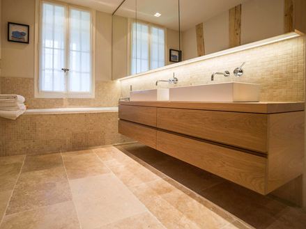 Bagno moderno con lavabo in legno, ampie finestre e piastrelle in travertino beige