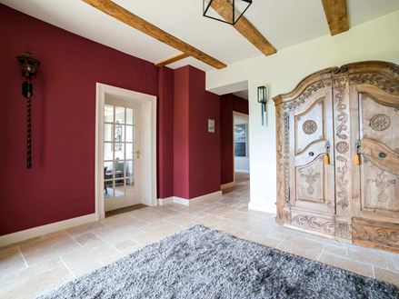 Ingresso con armadio in legno, parete rossa e piastrelle in travertino beige.