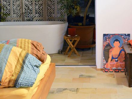 Camera da letto con cuscini colorati e pavimento in pietra calcarea di Solnhofen