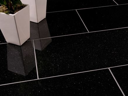 Due vasi di fiori bianchi su piastrelle di granito Star Galaxy scuro con fughe strette e chiare