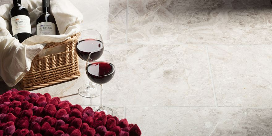 Due bicchieri da vino accanto a un cestino di fragole pieno su piastrelle di marmo lucido Silver Shadow