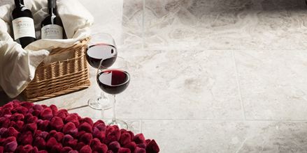 Due bicchieri da vino accanto a un cestino di fragole pieno su piastrelle di marmo lucido Silver Shadow