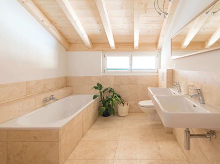 Piastrelle in travertino Classic Light in un bagno con vasca