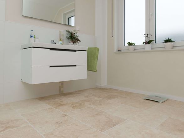 Piastrelle in travertino chiaro in un bagno moderno con mobili bianchi
