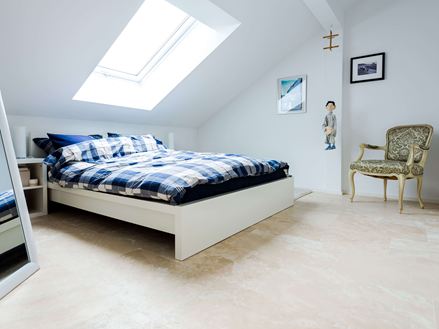 Una luminosa camera da letto sotto il tetto con pavimentazione in travertino Medium Line