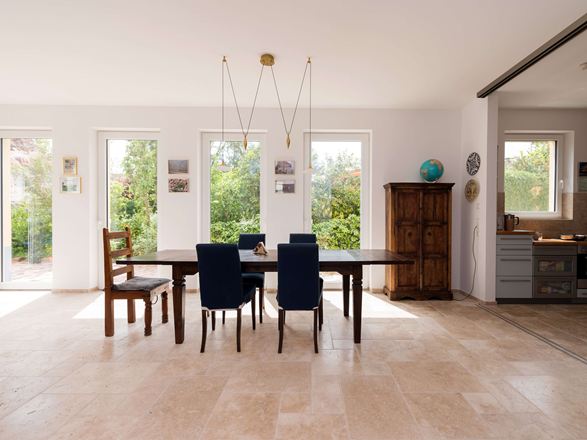 Luminosa zona pranzo con mobili in legno e pavimento in piastrelle di travertino beige