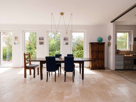 Luminosa zona pranzo con mobili in legno e pavimento in piastrelle di travertino beige