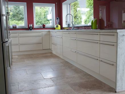 Foto cliente di una cucina con mobili bianchi, pareti rosse e piastrelle in travertino beige-marrone