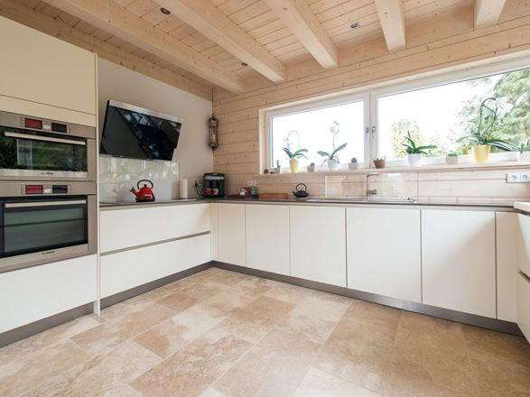 Cucina con mobili bianchi e pavimento in piastrelle di travertino rustico color beige