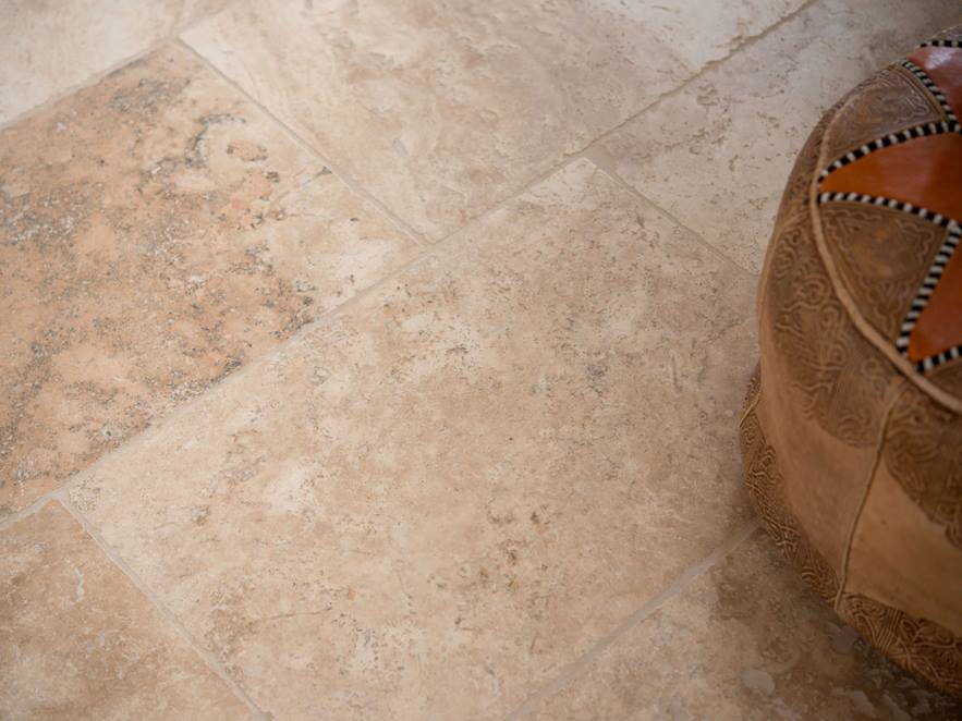 Piastrelle di travertino rustico posate in marrone e beige con cuscini decorativi