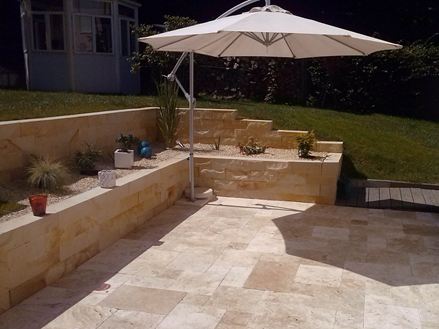 Foto cliente: lastre di ravertino Medium RV con ombrellone e muro in pietra
