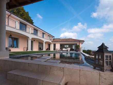 Vista della piscina e della casa con la lastra di travertino Light in un morbido colore beige