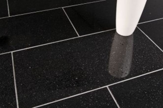 Un vaso bianco su piastrelle di granito nero con fughe chiare