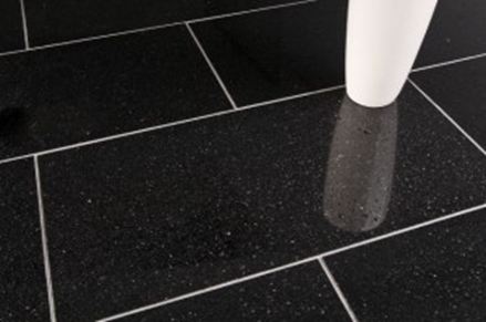 Un vaso bianco su piastrelle di granito nero con fughe chiare