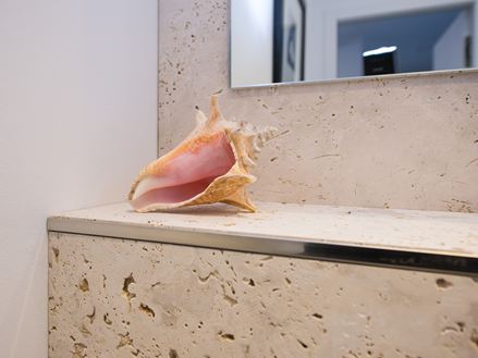 Rivestimento in travertino con decorazione a conchiglia in bagno