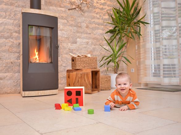 Il bambino gioca su un pavimento in pietra naturale davanti a un camino