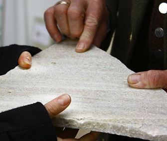 Due mani tengono un pezzo di pietra naturale di quarzite del Taunus