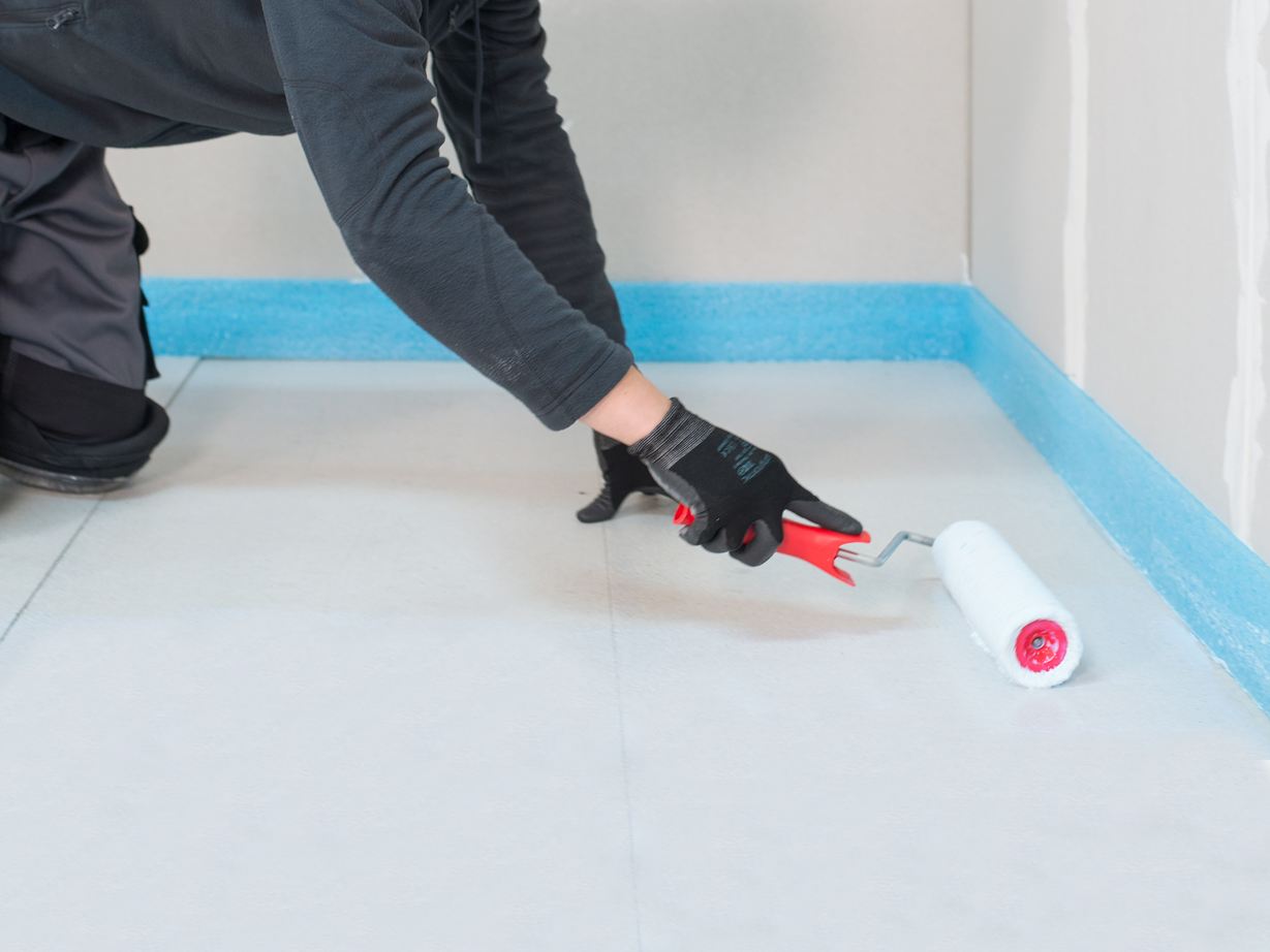 Il piastrellista applica il primer con un rullo