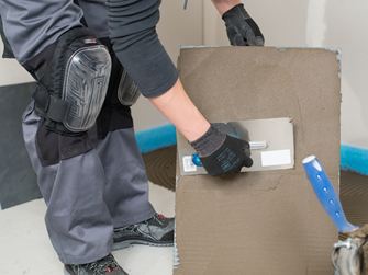 Un piastrellista applica l'adesivo sul retro delle Piastrelle