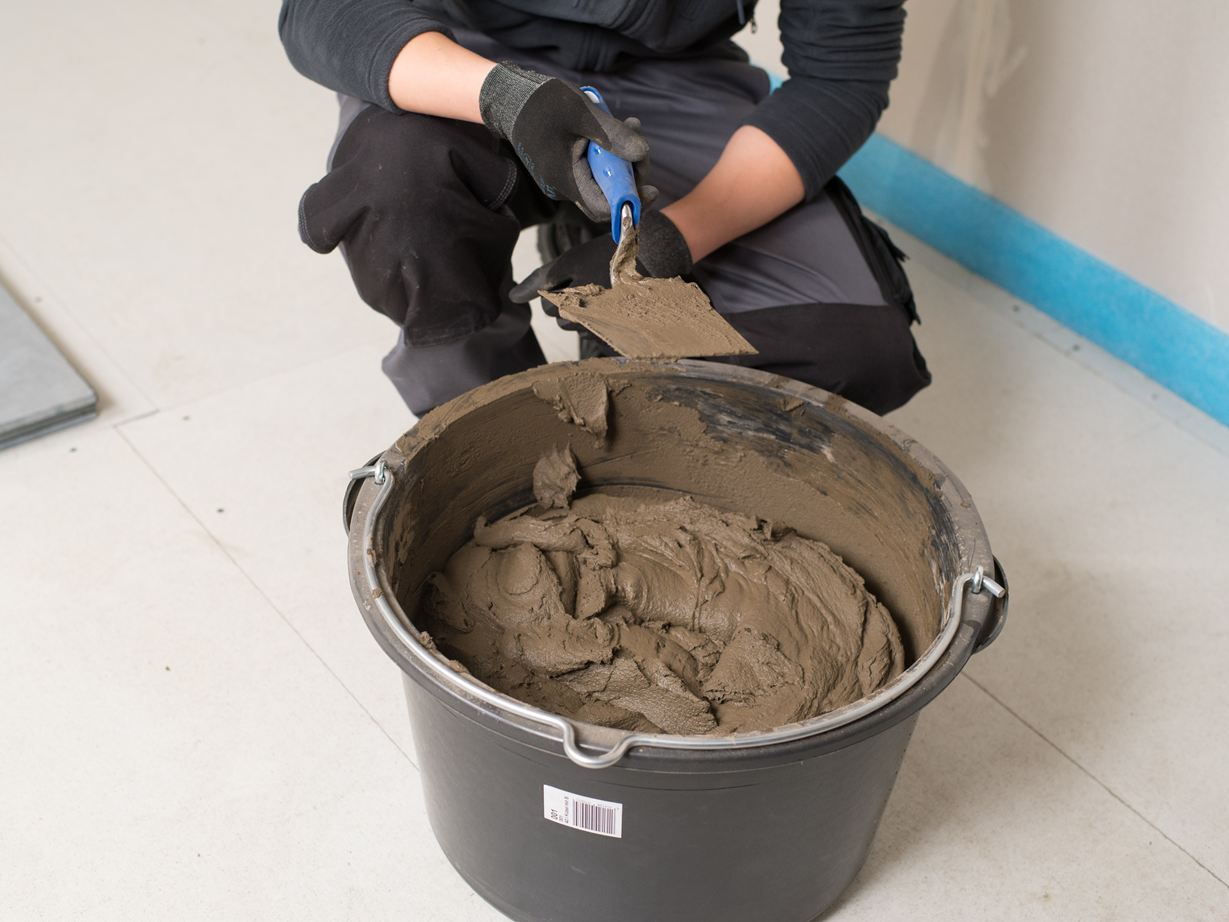 Piastrellista davanti a un secchio di colla per pietra naturale