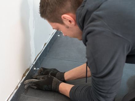 Il piastrellista installa i battiscopa