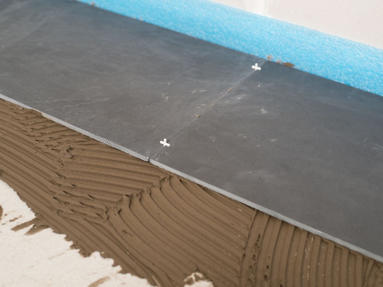 Croci di stuccatura come distanziatori tra due piastrelle di ardesia