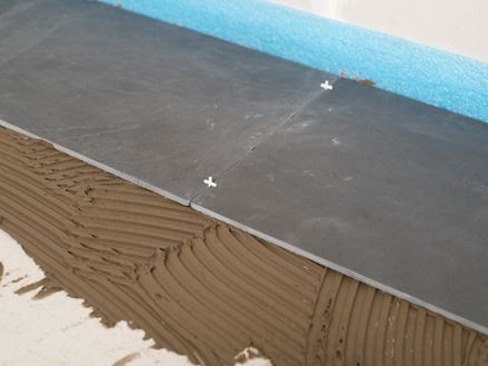 Croci di stuccatura come distanziatori tra due piastrelle di ardesia