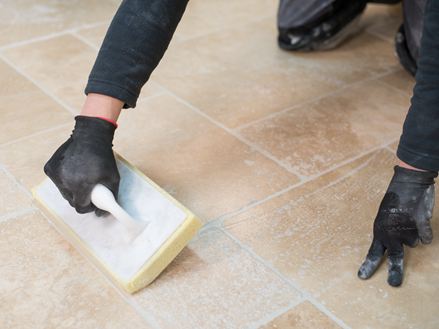 Il piastrellista pulisce il pavimento in travertino dopo la posa