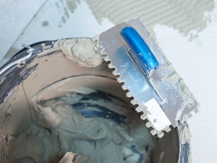 Un secchio di collante per pietra naturale e una spatola dentata