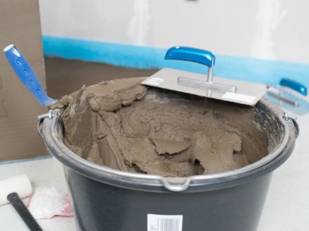 Un secchio di collante per pietra naturale e una spatola dentata