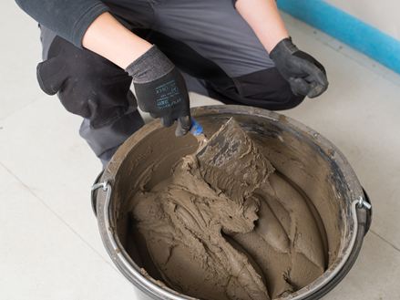 Il piastrellista mescola un secchio di malta per pietra naturale