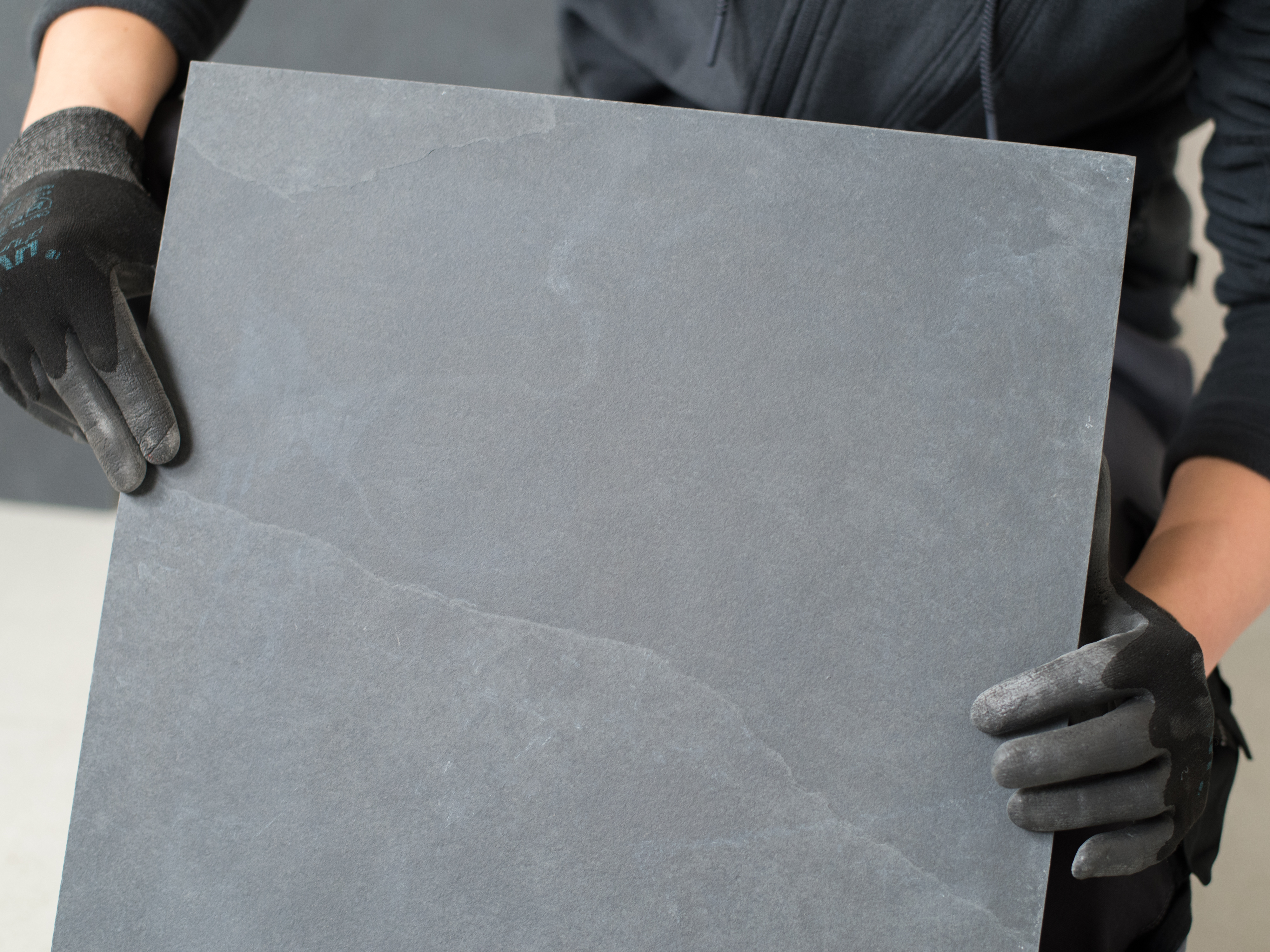 Il piastrellista tiene una piastrella di ardesia davanti alla telecamera