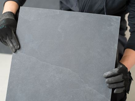 Il piastrellista tiene una piastrella di ardesia davanti alla telecamera