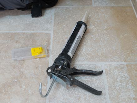 Cartuccia di silicone e spatola su un pavimento in travertino