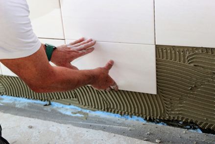 Premere leggermente per spingere le piastrelle nel letto adesivo.