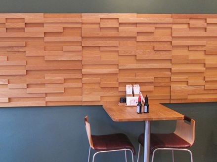 Un tavolo con due sedie davanti a una parete grigia con rivestimenti in legno marrone in un bistrot