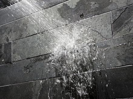 Acqua su una parete di pietra scura in bagno