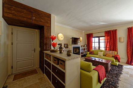 Soggiorno in stile mediterraneo con divano verde e tende rosse