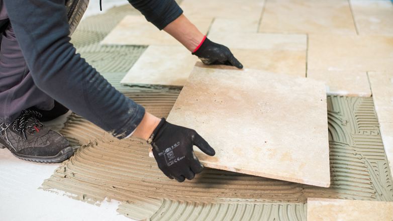 Un piastrellista posa una piastrella di travertino
